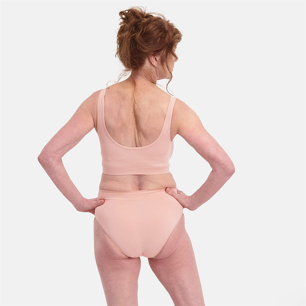 Kvinde set bagfra iført Sømløs Bambus Maxi Trusse i lys rosa med usynlig pasform og åndbare bambusmaterialer, designet til medium til stærk shaping til hverdag og fest.