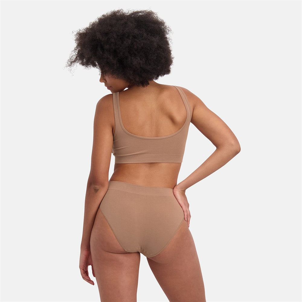 Kvinde set bagfra iført Sømløs Bambus Maxi Trusse i beige, med åndbare bambusmaterialer og medium til stærk shaping for en usynlig og komfortabel pasform.