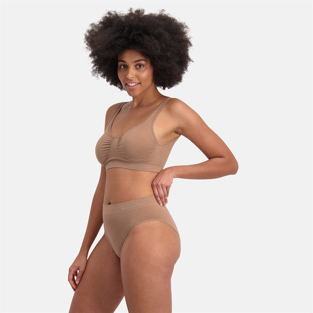 Kvinde iført Sømløs Bambus Maxi Trusse i beige, med åndbare og usynlige bambusmaterialer, der sikrer medium til stærk shaping og komfortabel pasform til hverdag og fest.