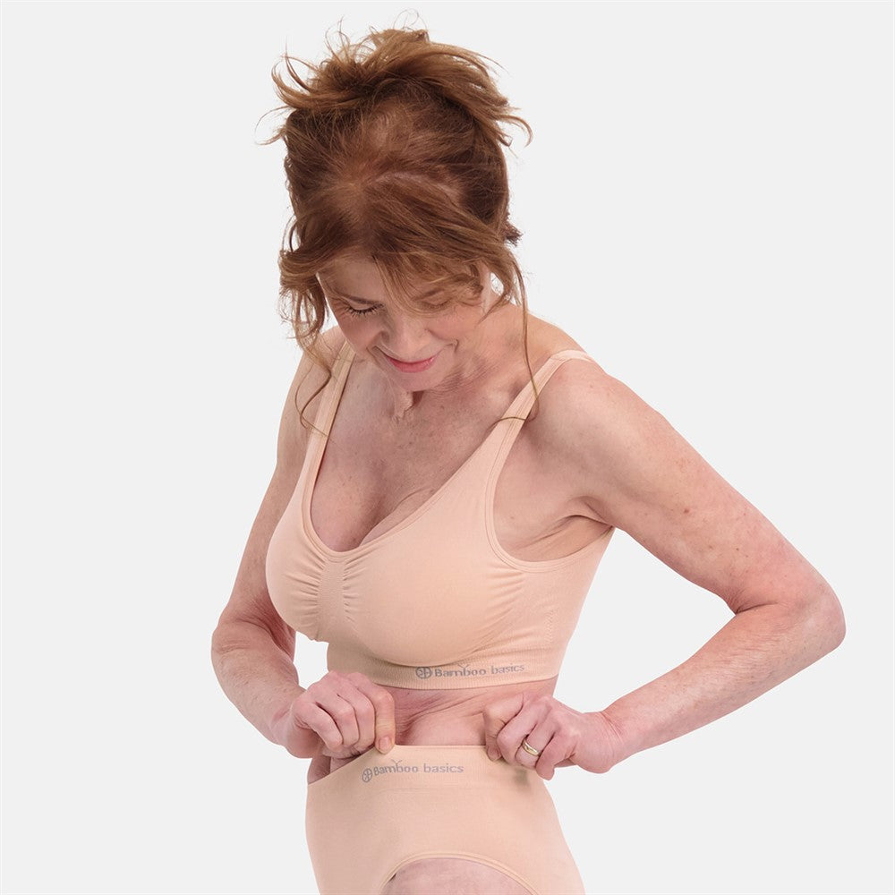 Kvinde iført Sømløs Polstret Bambus BH i lys nude farve med åndbart bambusmateriale og medium til stærk shaping, viser den usynlige sømløse pasform for optimal komfort.