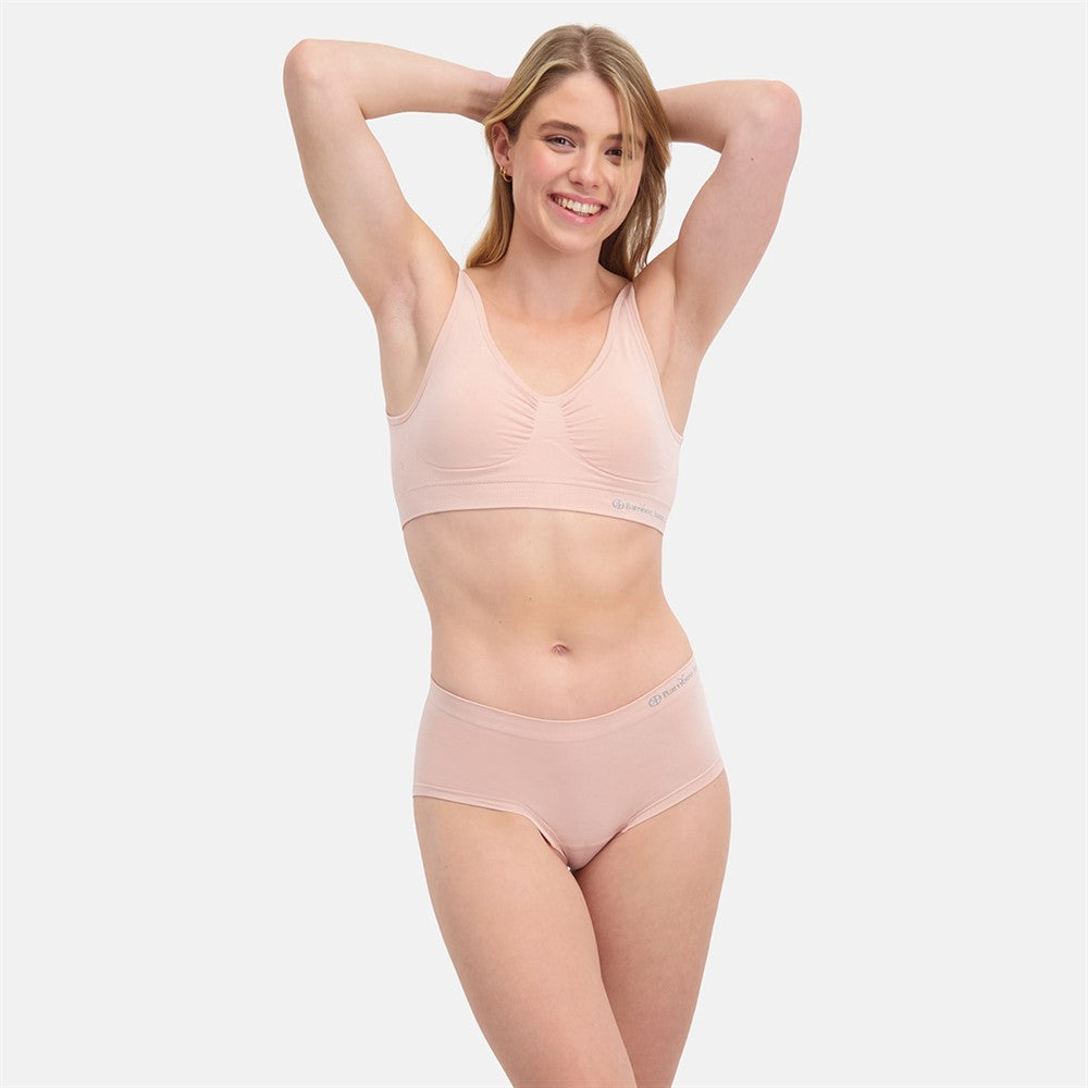 Kvinde i lyserød undertøj med usynlig pasform iført Sømløs Hipster trusse 2-pak i åndbare bambusmaterialer med medium til stærk shaping til hverdag og fest.