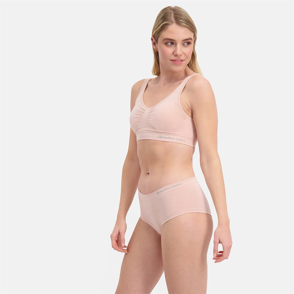 Kvinde iført Sømløs Hipster trusse 2-pak i åndbare bambusmaterialer med usynlig pasform og medium til stærk shaping, vist i blød lyserød farve.